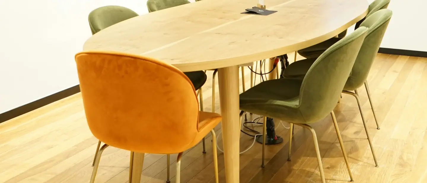 Ljust mötesrum med bord och stolar framför stora fönster